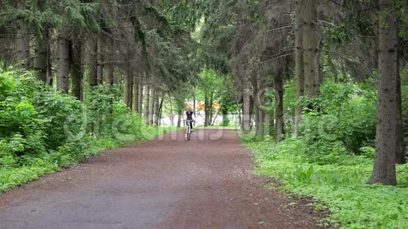 女人骑着自行车穿过绿色森林视频的预览图