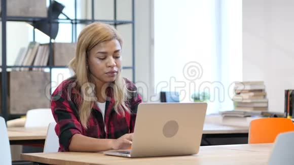 黑女人在笔记本电脑上工作微笑着走向镜头视频的预览图