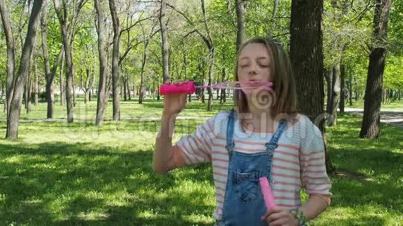 公园里有肥皂泡的十几岁女孩女孩在阳光明媚的日子里呼吸新鲜空气一个孩子在玩泡泡视频的预览图