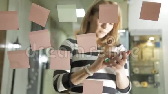 创意女商人准备在现代玻璃办公室进行头脑风暴使用不同颜色的贴纸视频的预览图