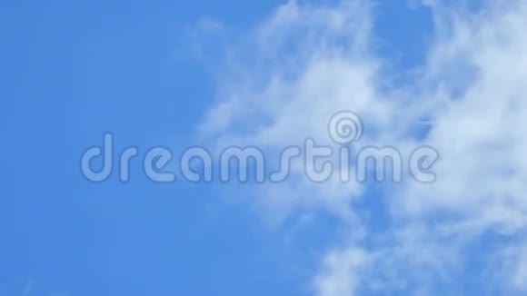 一架遥远的飞机从高空飞过在多云的蓝天上留下一个喷气式飞机的轨迹风视频的预览图