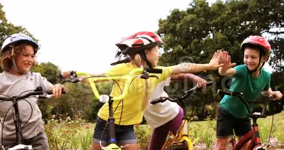 一群孩子骑着自行车站着高五视频的预览图