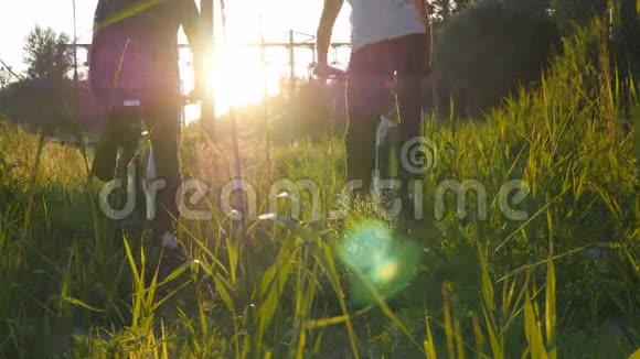 日落时分两名骑自行车的男子骑自行车穿过草地上的绿草朋友们骑着自行车穿过田野视频的预览图