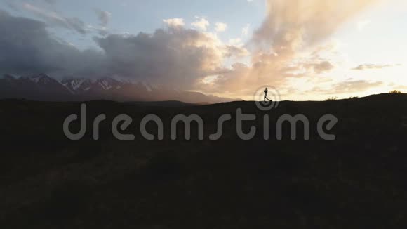 一个人走在路上日落时背光在群山之间云4k慢动作视频的预览图