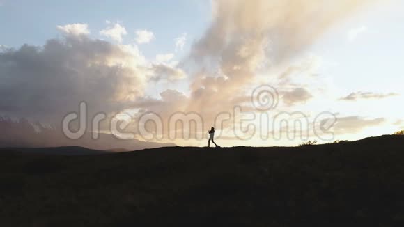 一个人走在路上日落时背光在群山之间云1080p慢运动视频的预览图