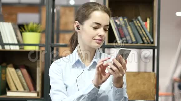女性听音乐带耳机智能手机视频的预览图