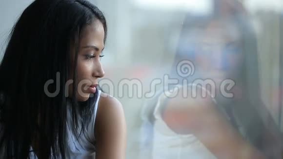 美丽的悲伤的女人看着窗户视频的预览图