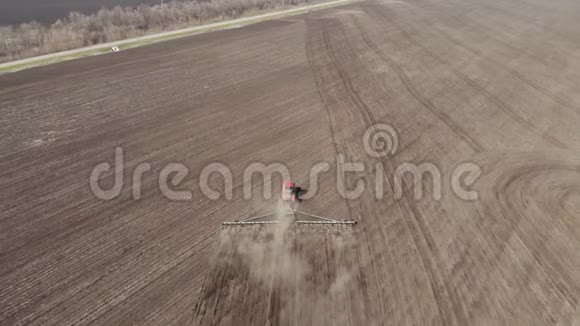 4空中镜头现代红色拖拉机在农业领域在阳光明媚的日子拖拉机耕地拖拉机培育视频的预览图