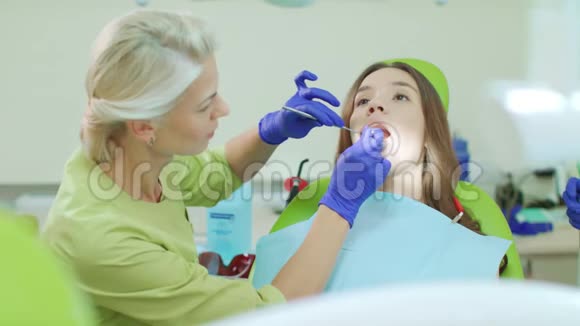 牙医用牙科工具检查病人的牙齿医生和病人视频的预览图