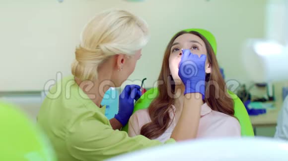 牙医用嘴镜检查病人的牙齿口腔医生和病人视频的预览图