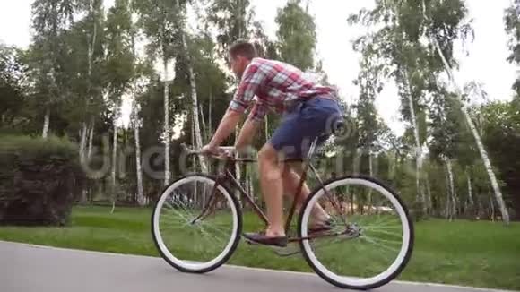 跟着年轻英俊的男子骑着一辆老式自行车户外运动男在公园骑自行车健康的生活方式视频的预览图