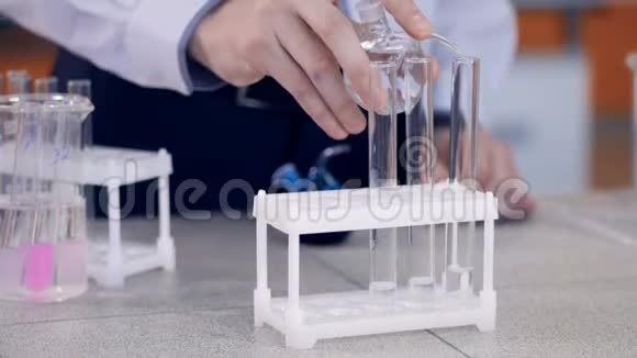 手将化学试剂加入小瓶试管中学生在实验室做化学测试视频的预览图