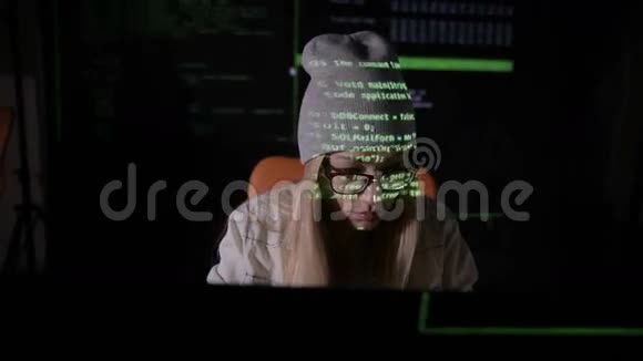 女性黑客在黑暗中在电脑里工作她脸上的二进制代码投影打滑头前景视频的预览图