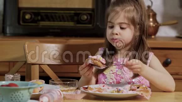 小女孩装饰和吃美味的纸杯蛋糕视频的预览图