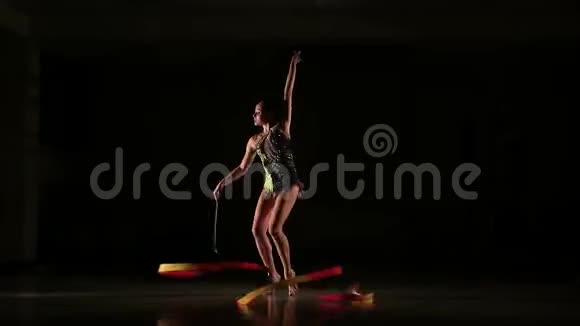 慢动作苗条可爱迷人的女孩运动员穿着鲜艳多彩的游泳衣用缎带表演艺术体操的元素视频的预览图