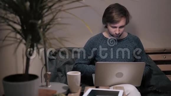 年轻的男性自由职业者坐在前面打开笔记本电脑在自然食品咖啡馆工作帅哥在读短信视频的预览图