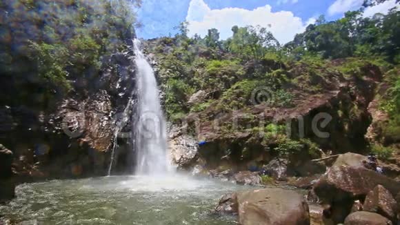 从顶部的绿色岩石中沿着泡沫溪流到池塘的瀑布视频的预览图