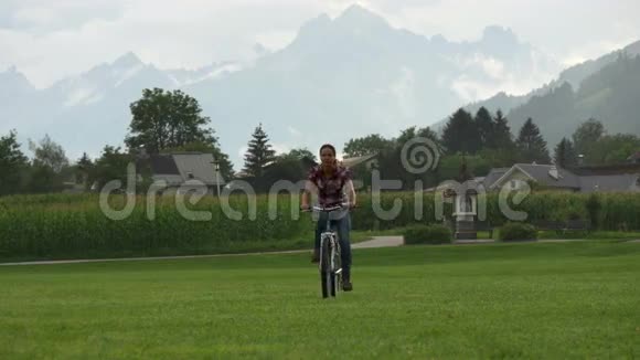 年轻女子骑自行车穿过绿色的田野视频的预览图