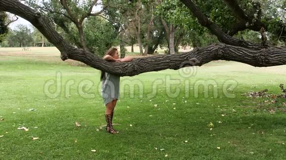 白种人少女站在树枝上看着树下移动视频的预览图