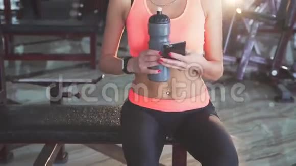 健康的女孩喝水用电话和在健身房跳舞视频的预览图