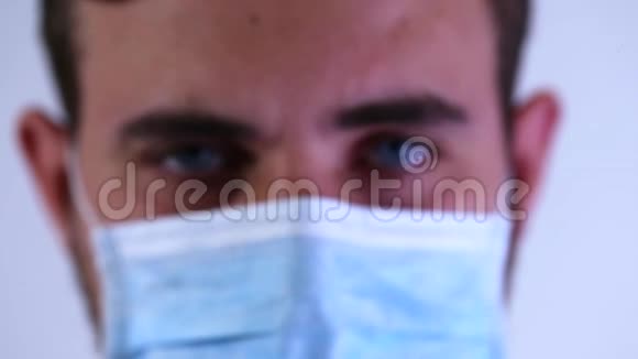 一个戴着外科口罩的医生看着摄像机的脸视频的预览图