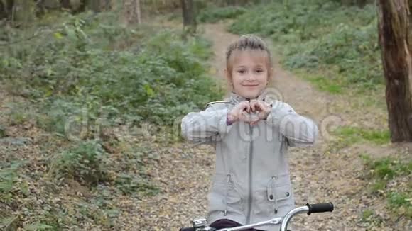 秋天的森林里一个快乐的小女孩骑着自行车视频的预览图