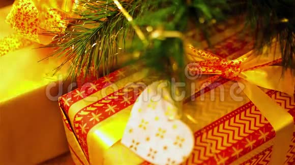 在人造圣诞树的树枝下放置礼物的特写盒子闪着黄色的香菜视频的预览图