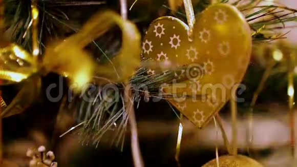 特写一件圣诞装饰金心挂在人造杉木上闪烁着黄灯的圣诞树花环视频的预览图