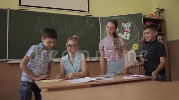 教室里的漂亮老师坐在桌子前问孩子们教育小学学习和人视频的预览图