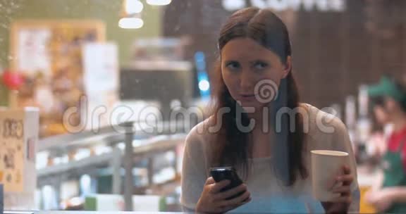 咖啡店里有智能手机的女人视频的预览图