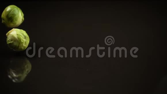 黑色背景下掉落的布鲁塞尔卷心菜视频的预览图