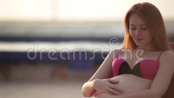 红头孕妇穿着泳衣在泳池边晒日光浴夏日心情视频的预览图