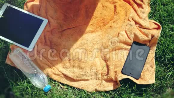 俯视美丽的年轻女子戴着太阳镜躺在草地上听着音乐唱着歌3840x2160视频的预览图