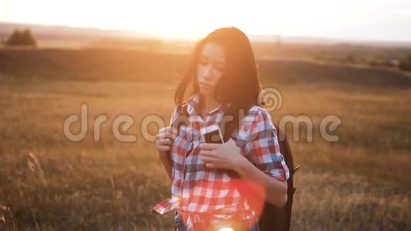 嬉皮青年女孩步行与背包智能手机享受日落在高峰后方背景视图下的游客视频的预览图