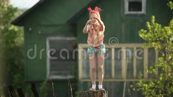 小可爱的滑稽女孩在院子里的树桩上跳舞视频的预览图