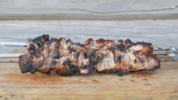烧烤中的熟肉放在木板上粗糙轻微烧焦的碎片背景木墙视频的预览图