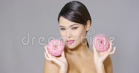 笑的女人拿着两个粉红色的甜甜圈视频的预览图