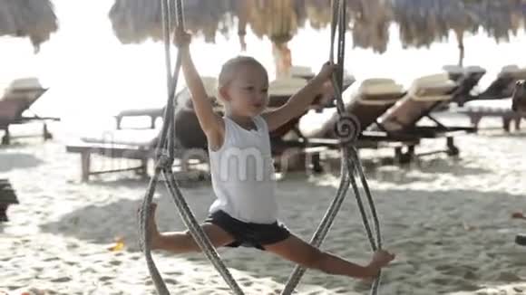 可爱的女婴在沙滩上的秋千上玩耍和做体操视频的预览图