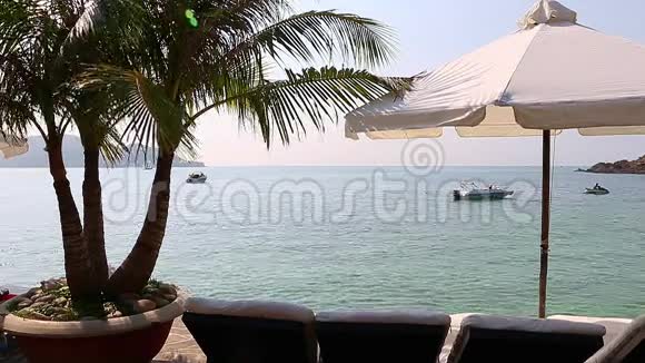 在海滩上晒太阳和雨伞在地平线上的船视频的预览图