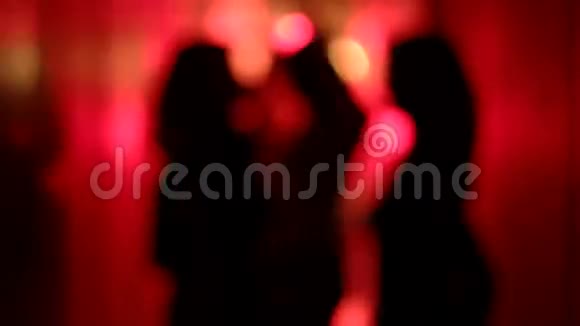 三个女人的剪影在一条模糊的红色走廊里跳舞她的手举起来视频的预览图