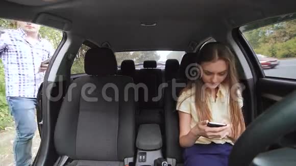 女孩在车里用电话男孩坐在车里用平板电脑讨论4K视频的预览图