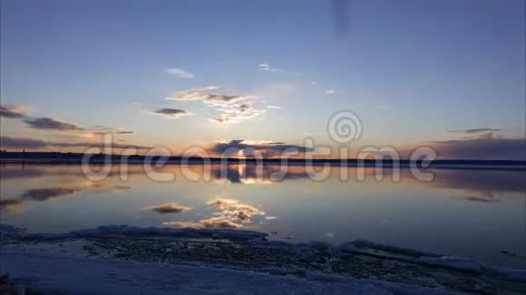 日落于一个大湖太阳躲在云层后面灰红色的云浮在湖面上冲浪板上的云视频的预览图