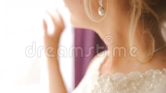 幸福的新娘透过窗户看着镜头微笑的肖像视频的预览图