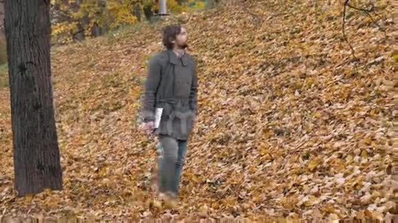 一个留着胡子的浪漫男人带着平板走进森林汽车的肖像公园里英俊的学生视频的预览图