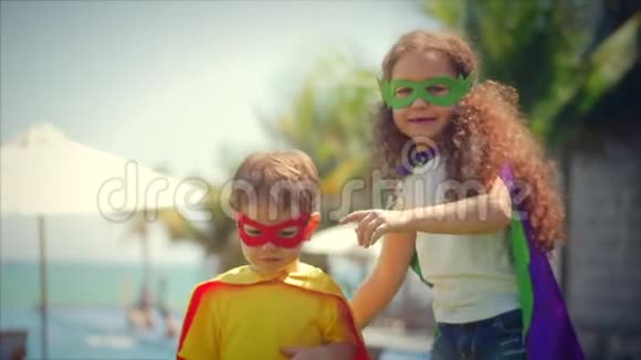 穿着超级英雄服装斗篷和面具的孩子们扮演着英雄在公园的夏日小路上玩得很开心视频的预览图