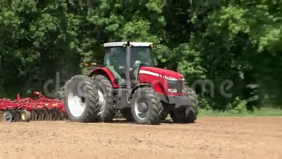 赤商用拖拉机牵引花在泥田晴天视频的预览图