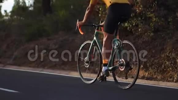 一个骑着运动型公路自行车的人在山上的公路上骑车视频的预览图
