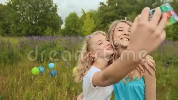 两个年轻的金发女孩在电话里被拍照做自拍视频的预览图