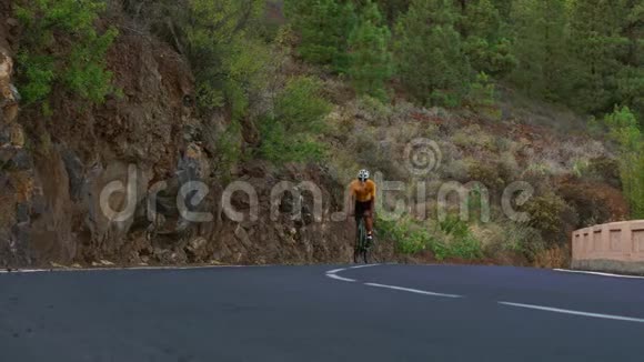 一个骑着运动型公路自行车的人在山上的公路上骑车视频的预览图