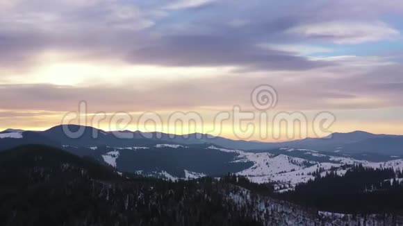 在雪山和山坡上针叶林令人惊叹的景观上鸟瞰蓝天视频的预览图